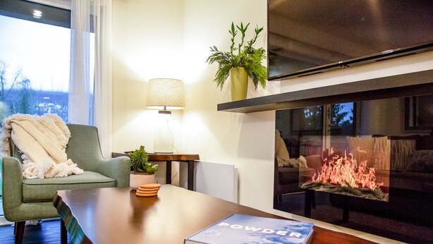 En moderne stue med pejs, sofa, sofabord og lampe.