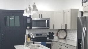 Uma cozinha moderna com ilha central, eletrodomésticos de aço inoxidável e iluminação pendente.