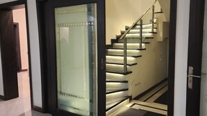 A modern staircase with glass railings and a metal handrail, leading to an upper floor. - Haven Lodge, 7BR stylish holiday home with hot tub & mountain view (Islamabad)