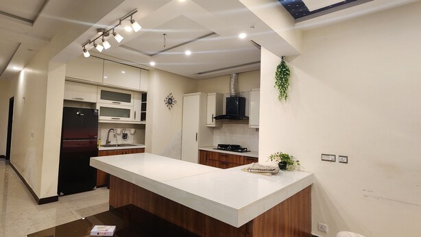 A modern kitchen with a central island, built-in appliances, and recessed lighting. - Haven Lodge, 7BR stylish holiday home with hot tub & mountain view (Islamabad)