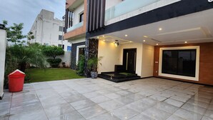 A modern building with a tiled patio, a black door, and a large window. - Haven Lodge, 7BR stylish holiday home with hot tub & mountain view (Islamabad)