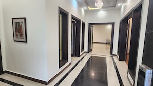 A hallway with black and white tiled flooring, dark wooden doors, and a framed picture on the wall. - Haven Lodge, 7BR stylish holiday home with hot tub & mountain view (Islamabad)
