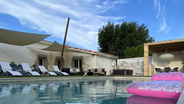 Una piscina con sillas de descanso y una zona con sombra.