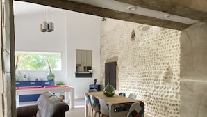 Un comedor con pared de piedra, techo de madera y una mesa con sillas.