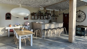 Un comedor con una mesa y sillas de madera, una barra con taburetes y un techo decorativo.