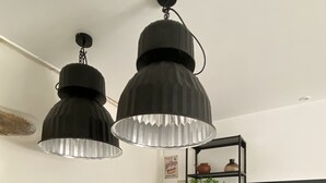 Una cocina con encimeras de madera, un estante negro y luces colgantes.