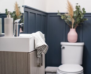 Ein Badezimmer mit Waschbecken, Spiegel, Handtuch, Toilette und einem Blumentopf.