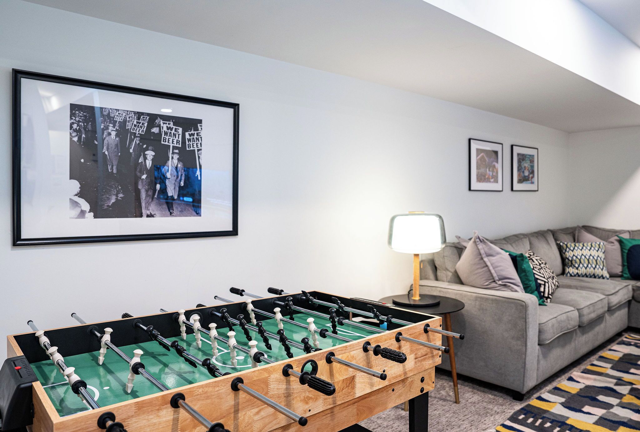A room with a foosball table, a sofa, and framed pictures on the wall.