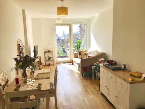 A spacious living area with a dining table, a sofa, and a kitchen area with cabinets.