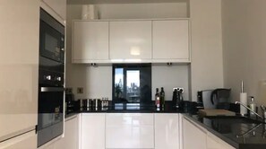 A modern kitchen with white cabinets, a black countertop, and a window with a city view.