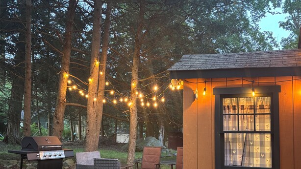 A wooden deck with outdoor furniture, a barbecue grill, and string lights.