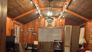 A cozy living room with a wooden ceiling, a television, a sofa, a chair, and a coffee table.
