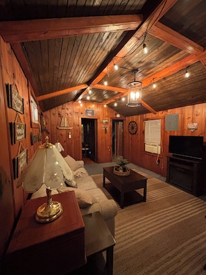 Un intérieur chaleureux en bois, avec un canapé, une table basse, une lampe et un téléviseur.