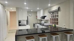 Una cocina moderna con una isla central, taburetes de bar y un comedor.