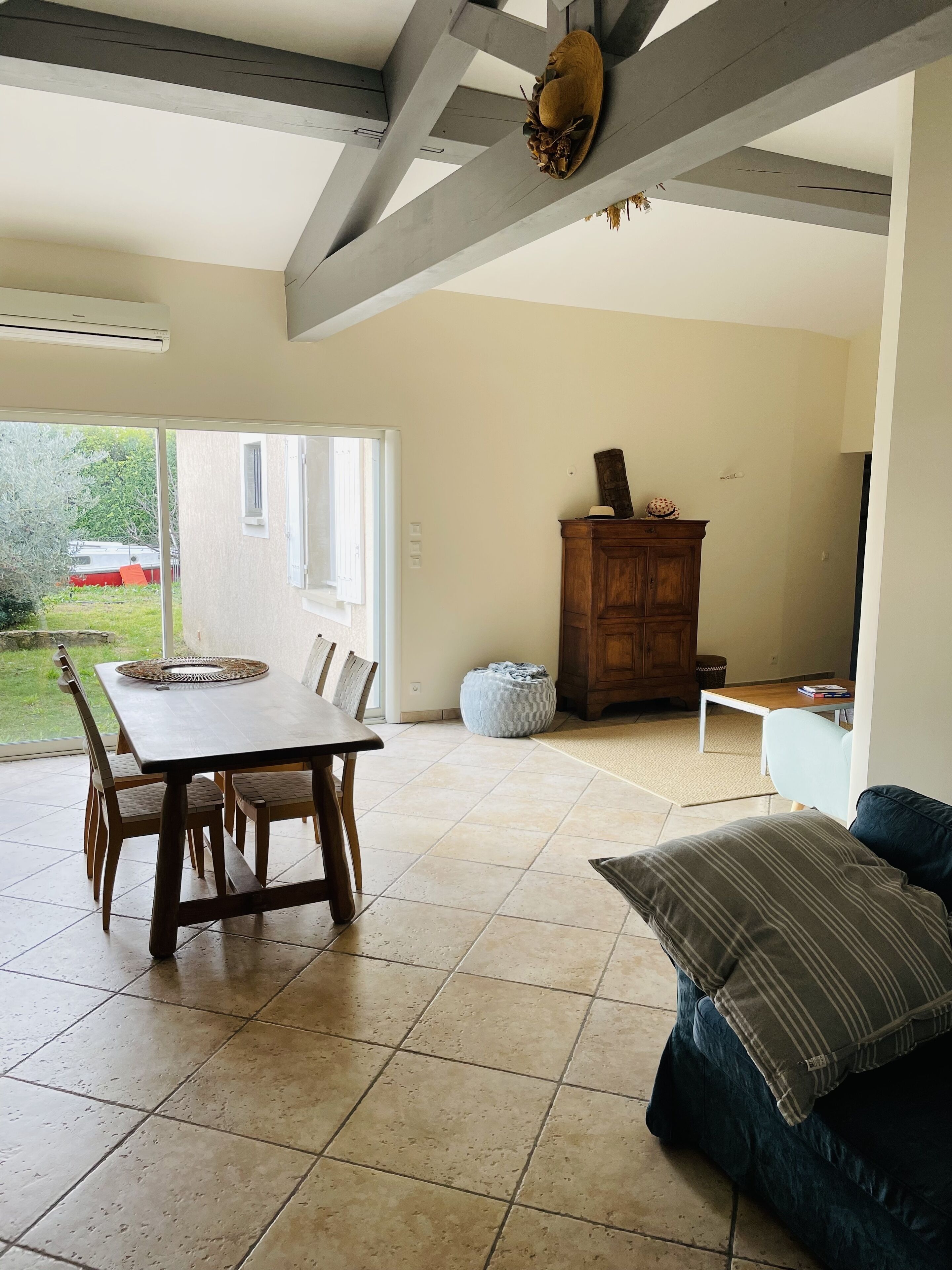 A spacious living area with a dining table, a sofa, and a wooden cabinet.