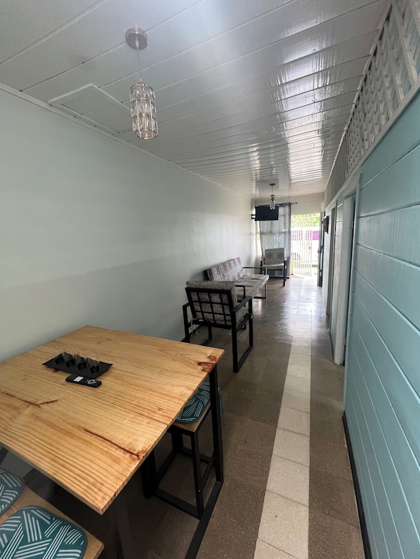 A corridor with a wooden table and chairs, a hanging light fixture, and a blue wall.