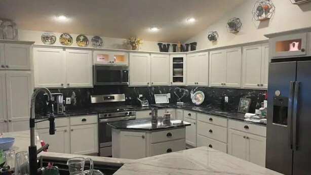 A modern kitchen with white cabinets, a black countertop, and a marble island. - Stunning Golf Front 3 BR Villa in The Villages (THE VILLAGES)
