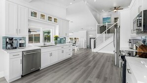A modern kitchen with white cabinetry, stainless steel appliances, and a wooden floor. -  Luxury WaterFront Home, Putting Green, Bocce, Pool/PPong Tbl (Marco Island)
