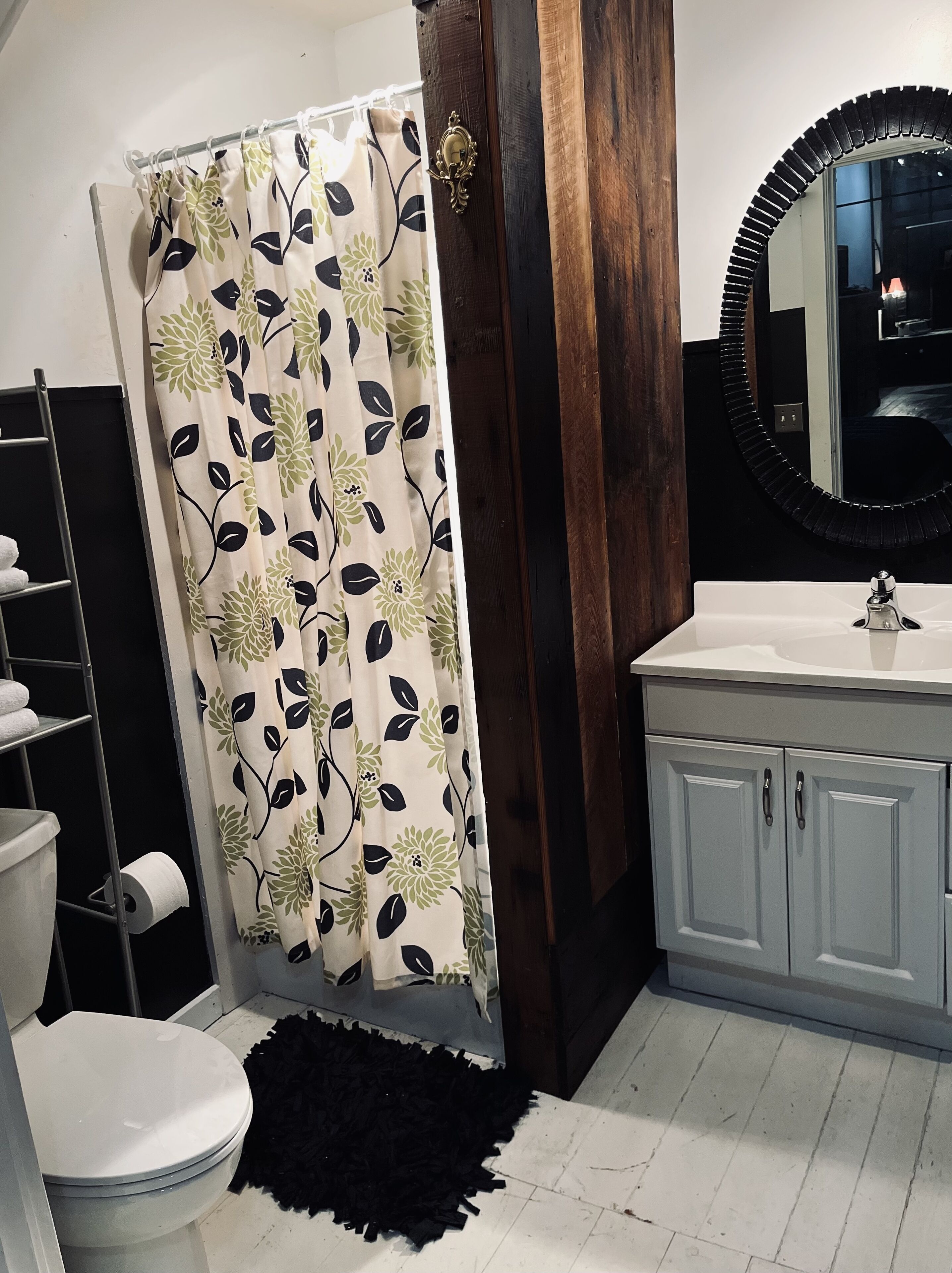 A bathroom with a toilet, a sink, a mirror, and a shower curtain with a floral pattern.
