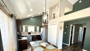 A modern kitchen with a dining area, wooden flooring, and a view of the living area. - ABQ Home Overlooking Mountain- Near Sandia Tramway + Balloon Fiesta  (Albuquerque)