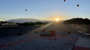 A rooftop terrace with a view of the sunset, hot air balloons, and outdoor seating. - ABQ Home Overlooking Mountain- Near Sandia Tramway + Balloon Fiesta  (Albuquerque)