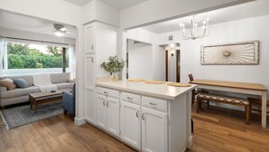 Una cucina moderna con mobili bianchi, un'isola centrale e un'area pranzo con una panca.