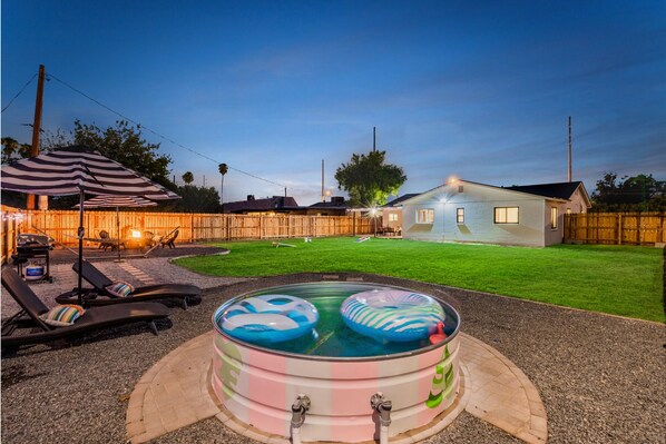 Un jardin avec une piscine, des chaises longues et une maison.