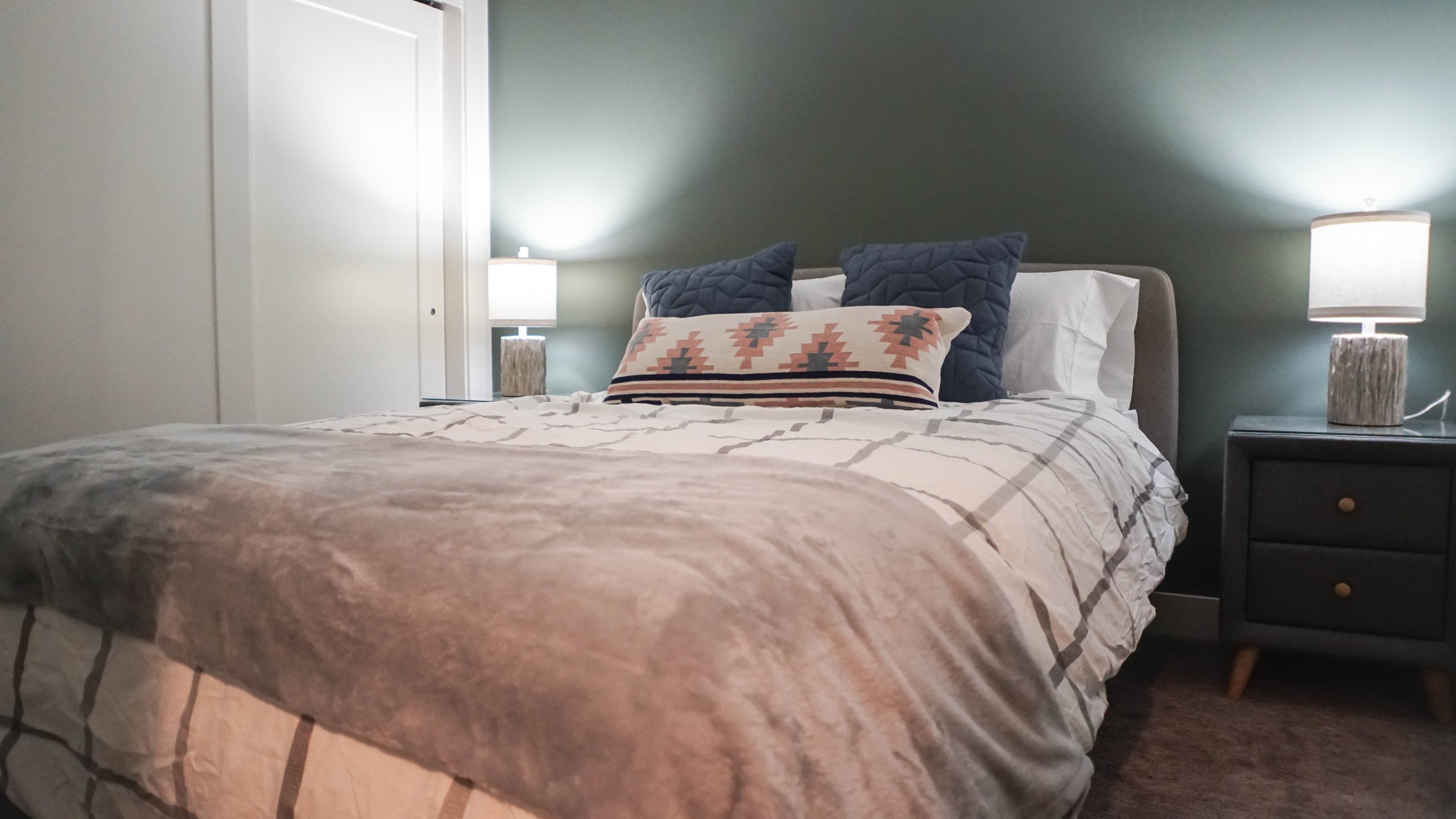 A bedroom with a bed, two bedside tables with lamps, and a door.