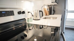 Uma cozinha moderna com fogão de aço inoxidável, chaleira e cafeteira.