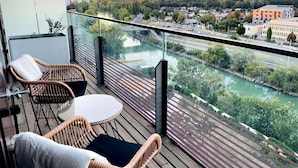 A balcony with wicker furniture and a view of a river and cityscape. - Sunrise over the park (Prater) and roof terrace pool (Wien)