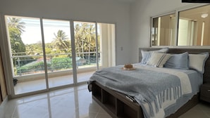 A bedroom with a bed, a ceiling fan, a large window, and a view of greenery outside. - Caribbean style villa directly on the beach (Cabarete)