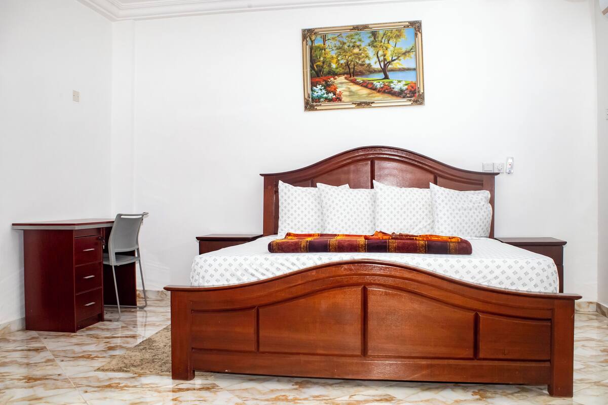A bedroom with a wooden bed, a desk, and a chair.