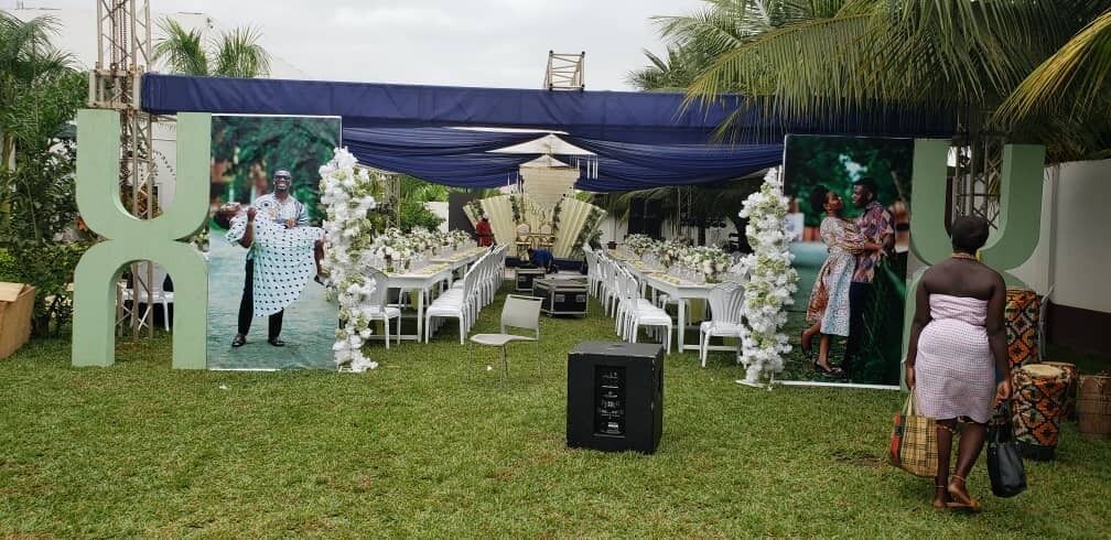 Allestimento per un evento all'aperto con tenda, tavoli, sedie e un palco.