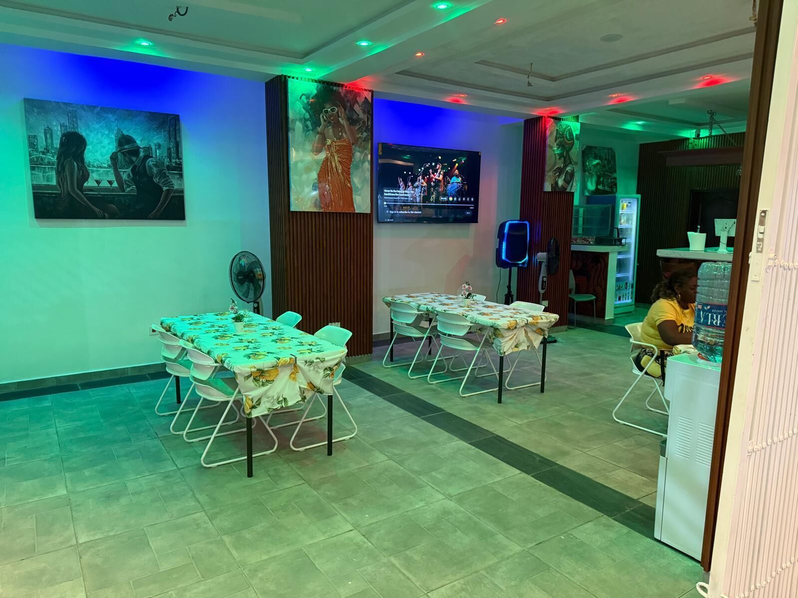 A conference room with tables, chairs, a TV, and artwork on the walls.