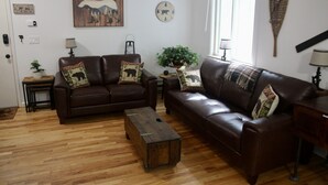 A living room with two brown leather sofas, a wooden coffee table, and a potted plant. - Enjoy the Lower Catskills (Woodridge)