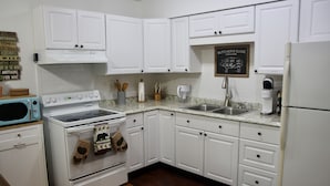 A kitchen with white cabinets, a stove, a microwave, a sink, and a refrigerator. - Enjoy the Lower Catskills (Woodridge)