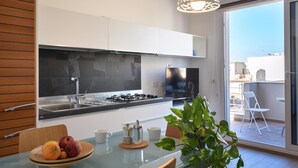 A modern kitchen with a gas stove, a large window, and a dining area with a table and chairs. - Lovely apartment in Pozzallo with WiFi (Pozzallo)