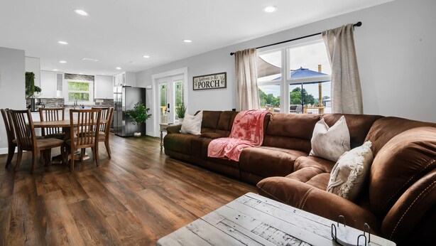 A modern living room with a brown leather sofa, wooden dining table, and a white coffee table. - Modern farmhouse cottage (Okeechobee)