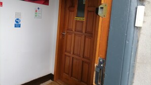 Una puerta de madera con un cartel que dice 'PRECAUCIÓN' y un cartel que indica 'Apagar cuando no se use', además de una pintura de una rosa roja en la pared.