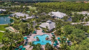 Eine Vogelperspektive zeigt ein Resort mit einem zentralen Schwimmbecken, mehreren Gästevillen und üppiger Bepflanzung.