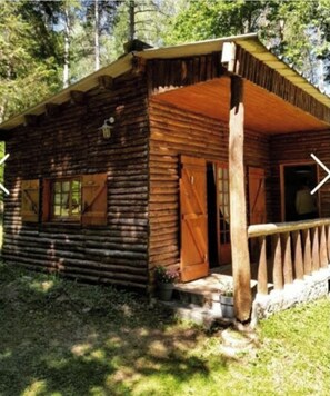 Une cabane rustique en rondins de bois, dotée d’un porche et d’un petit hall d’entrée.