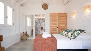 A bedroom with a bed, a wooden wardrobe, a woven basket, and a wall-mounted clock. - Villa Rackam, balcony on the Baie des Saintes with pool and 300m from beaches (Terre-de-Haut)