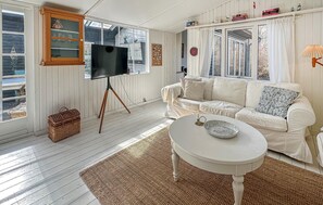 A living room with a white sofa, a television on a tripod stand, a small table with a bowl, and a wicker basket. - Amazing home in Gilleleje with sauna (Gilleleje)