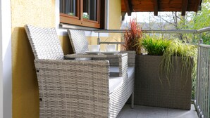 Een set van een rieten stoel en tafeltje op een balkon, met een bloempot.