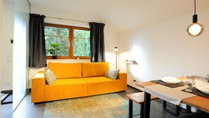 Een moderne woonkamer met een geel bankje, een eettafel en een raam met gordijnen.