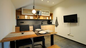 Een moderne keuken met een eethoek, voorzien van een magnetron, fornuis en een flatscreen televisie.