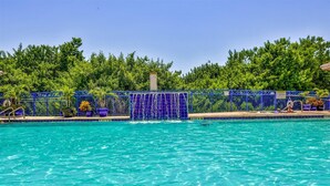 A swimming pool with a blue fence, surrounded by lush greenery.