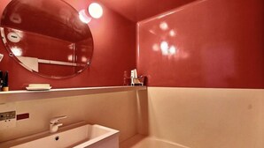 Een badkamer met een ronde spiegel, een wastafel en een bad.