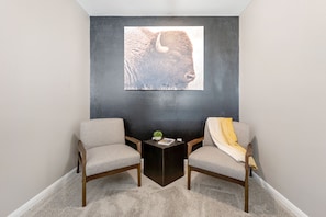 A room with two armchairs, a small side table, and a wall-mounted artwork of a bison.