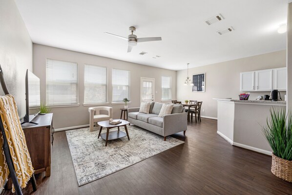 A spacious living room with a sofa, coffee table, and a dining area with chairs and a table.